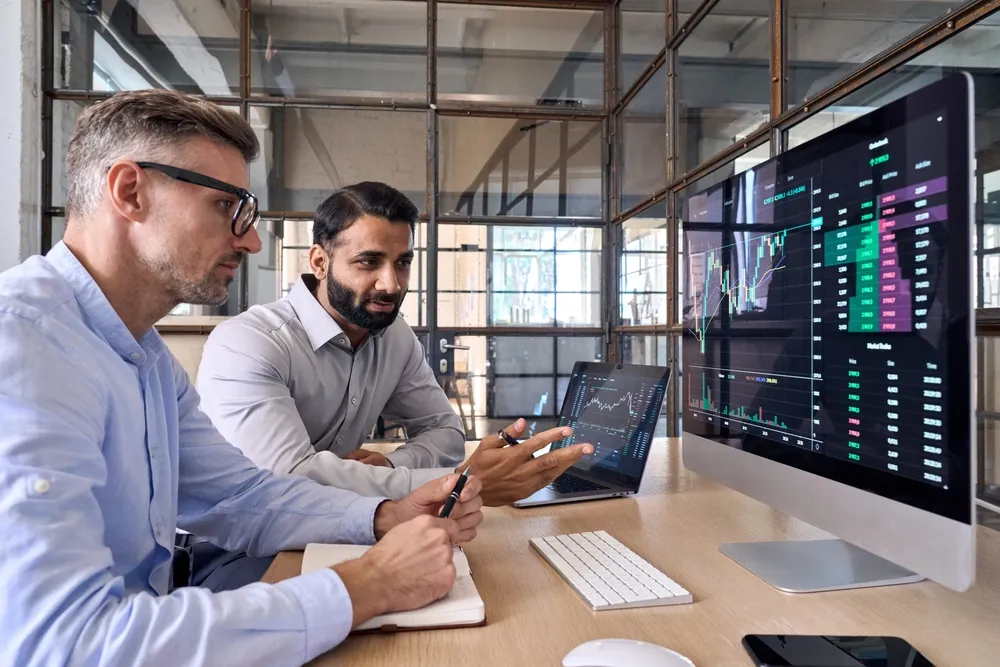 Project managers reviewing data dashboards on a large monitor