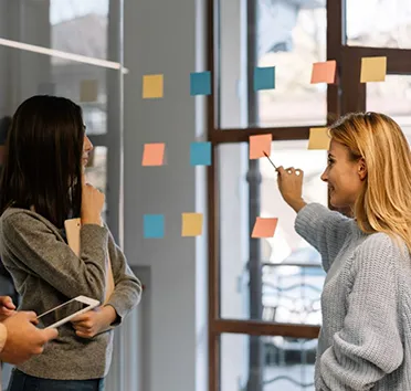 Colleagues planning a project with sticky notes on a glass wall