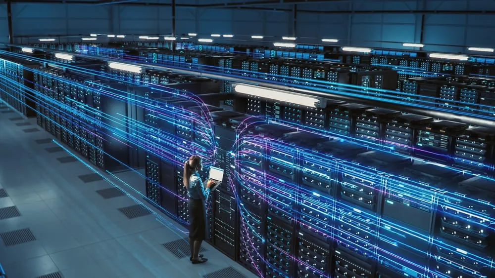 Engineer working between server racks in a large data centre